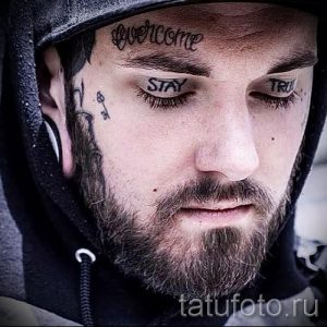 Фото тату: надписи "Overcome", "Stay", "True" на лице мужчины. Черно-белая татуировка, выполненная в минималистичном стиле.