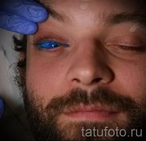 Фото тату: процесс окрашивания радужной оболочки глаза в голубой цвет, медицинская процедура, экстремальная модификация тела, работа мастера.