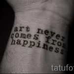 Фото тату: надпись 'art never comes from happiness' на запястье. Простой шрифт и минималистичный дизайн.