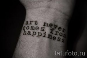 Фото тату: надпись 'art never comes from happiness' на запястье. Простой шрифт и минималистичный дизайн.