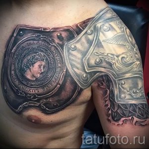 Фото тату на груди: детализированные доспехи с изображением бюста античного воина. Черно-серые тона, сложная проработка деталей и теней.