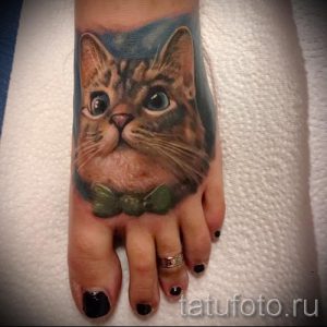 Фото тату милого кота в бабочке на стопе. Яркий и забавный рисунок, выполненный в мультяшном стиле. Идеально для любителей животных и оригинальных татуировок.