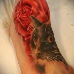 Фото тату кота, выглядывающего из букета красных роз на стопе. Яркий и красочный рисунок, выполненный в акварельной технике. Идеально для любителей цветов и животных.