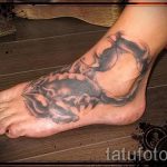 Фото тату скорпиона на стопе, выполненное в стиле blackwork. Использованы плотные черные заливки и геометрические элементы.