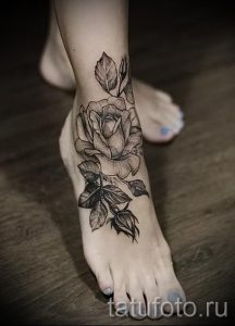 Фото тату розы на стопе, выполненное в технике black and grey. Детально проработанная роза с листьями, выполненная в оттенках серого.