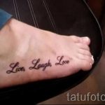 Фото тату надписи 'Live, Laugh, Love' на женской стопе. Черная надпись выполнена каллиграфическим шрифтом, располагается вдоль подъема стопы.