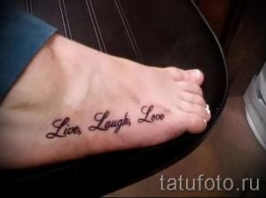 Фото тату надписи 'Live, Laugh, Love' на женской стопе. Черная надпись выполнена каллиграфическим шрифтом, располагается вдоль подъема стопы.