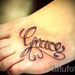 Фото тату на стопе: надпись 'Grace' выполненная каллиграфическим шрифтом с добавлением декоративных элементов в виде листьев и завитушек.