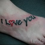 Фото тату надписи 'I Love You' с красным сердцем вместо буквы 'O' на стопе. Черный контур, яркий акцент, романтичный стиль. Идеально для пар.
