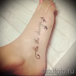 Фотография татуировки на стопе с надписью 'Be the change...' и изображением трех летящих птиц, выполненных черными чернилами.