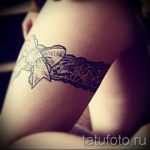 Фото тату подвязки с бантом, выполненной в черно-белой гамме. Детализированный рисунок татуировки на бедре.