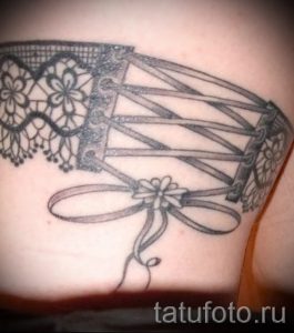Фото тату корсета, выполненного в технике blackwork на спине. Детализированный рисунок татуировки с акцентом на кружевные элементы.