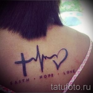 Фото татуировки на спине: пульс, крест, сердце и надпись 'Faith, Hope, Love'. Минималистичный дизайн, черные линии, религиозный смысл.