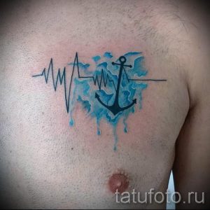 Фото тату на груди: Электрокардиограмма переходит в изображение якоря, залитого акварельными синими красками. Оригинальный рисунок татуировки.