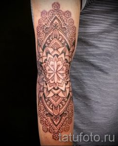 Фото тату: сложная мандала в стиле дотворк на предплечье, выполненная в оттенках серого. Детализированный рисунок татуировки с геометрическими узорами.
