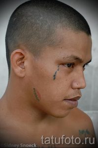 Фото тату: капли слез под глазом мужчины. Рисунок татуировки выполнен черными чернилами, символизирует печаль, потерю или раскаяние.