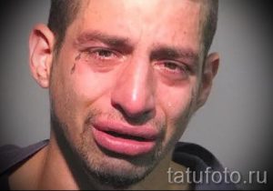 Фото тату: черная капля слезы под глазом мужчины. Небольшой, но выразительный рисунок татуировки, символизирующий печаль или потерю.