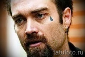 Фото тату: одиночная черная капля под глазом мужчины. Небольшой, но выразительный рисунок татуировки, символизирующий печаль или потерю.