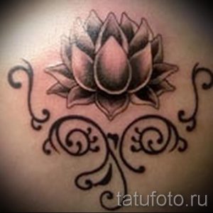 Фото тату: небольшая черно-серая татуировка лотоса на пояснице, украшенная узорами. Изящный и лаконичный дизайн.