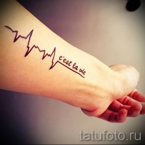 Фото тату: татуировка на руке, изображающая линию кардиограммы и фразу 'c'est la vie' на французском языке.