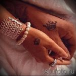 Фотография двух рук, держащихся вместе, с парными татуировками в виде короны на одной руке и маленькой короны на другой, символизирующими короля и королеву.