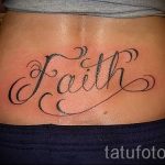 Фото тату: Черно-белая татуировка надписью 'Faith' на пояснице, выполненная каллиграфическим шрифтом.