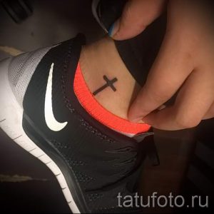 Фото тату: маленькое черное тату креста на лодыжке. Простой и лаконичный рисунок татуировки, символ веры и надежды.