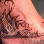 Фото тату на лодыжке: белый голубь с расправленными крыльями и надписью 'Faith' (Вера). Символ надежды и духовности.