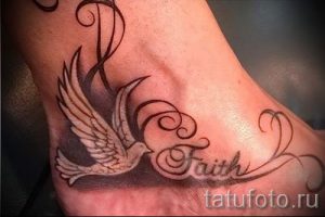 Фото тату на лодыжке: белый голубь с расправленными крыльями и надписью 'Faith' (Вера). Символ надежды и духовности.