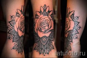 Фото тату: черно-белая татуировка на предплечье, изображающая розу, окруженную ажурным кружевом. Рисунок отличается высокой детализацией и реалистичностью.