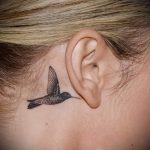 Фото тату: маленькая татуировка колибри на затылке, выполненная в технике blackwork. Изящный и минималистичный рисунок.
