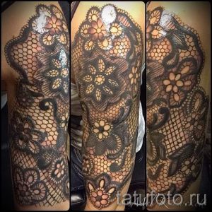 Фото тату: рука, полностью покрытая узором, имитирующим кружево с вплетенными цветами. Детализированный рисунок создает эффект объемности и изысканности.