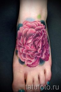 Фото тату большого розового пиона на стопе. Детализированные лепестки, реалистичные тени, яркие цвета. Идеи для женских татуировок на ноге.