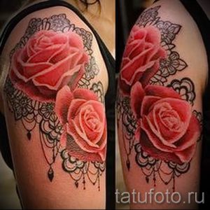 Фото тату: две розовые розы, обрамленные черным кружевом, украшают плечо девушки. Мягкие оттенки и изящные линии создают романтичный образ.