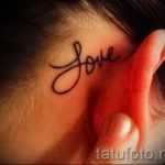 Фото тату: Простая и стильная татуировка с надписью 'Love', выполненная черными чернилами за ухом. Идеальный выбор для романтичных натур.