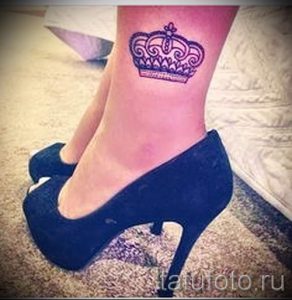 Фото тату изящной короны, выполненной в фиолетовом цвете, на женской лодыжке.