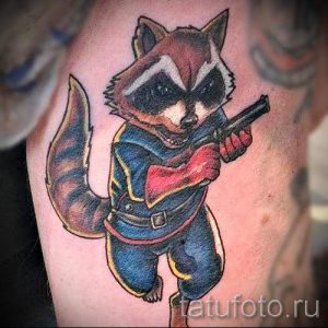 Фото тату енота Ракеты из Стражей Галактики с оружием. Яркий и детализированный рисунок в мультяшном стиле.