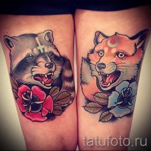 Фото пары татуировок на бедрах: енот с розой и лиса с цветком. Рисунки выполнены в ярком традишнл стиле.
