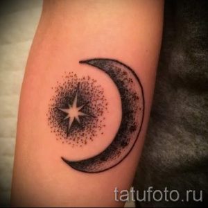 Фото тату с изображением полумесяца, внутри которого находится яркая звезда, окруженная точками. Рисунок татуировки выполнен в черных тонах с добавлением текстуры.