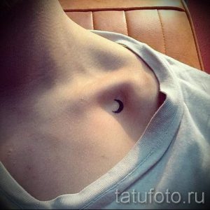 Фото тату: Маленькая черно-серая татуировка полумесяца на ключице девушки. Минималистичный рисунок татуировки с четкими линиями.