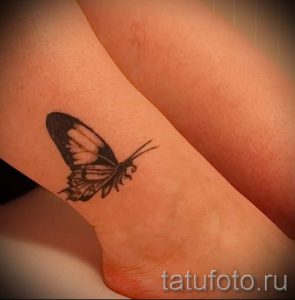 Фото татуировки с изображением крыла бабочки на лодыжке. Детализированный рисунок татуировки выполнен в черно-белой гамме, символизируя красоту и трансформацию.
