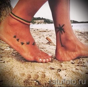 Фото татуировок на лодыжках: на одной ноге изображена пальма, на другой – летящие птицы. Яркий и летний дизайн.
