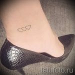 Фото татуировки с изображением двух маленьких сердец на лодыжке. Минималистичный рисунок татуировки выполнен тонкими линиями, символизируя любовь и привязанность.