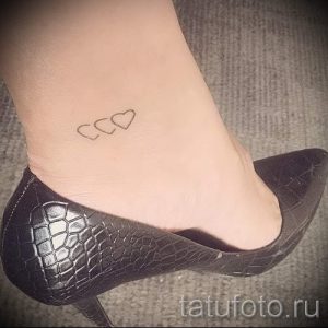 Фото татуировки с изображением двух маленьких сердец на лодыжке. Минималистичный рисунок татуировки выполнен тонкими линиями, символизируя любовь и привязанность.