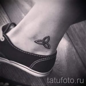Черно-белое фото тату кельтского узла на лодыжке. Минималистичный рисунок татуировки выполнен тонкими линиями, подчеркивающими изящество узора.