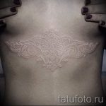 Фото тату: изящная мандала, выполненная белыми чернилами на груди. Идея для женской татуировки в стиле white ink.