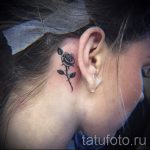 Фото тату: изящная татуировка розы, выполненная в черно-серых тонах, расположена на затылке девушки. Классический выбор для любителей цветочных мотивов.