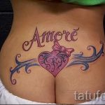 Фото тату: надпись "Amore" (любовь) и изображение сердца с бантиком на пояснице. Романтичный эскиз тату для девушек.