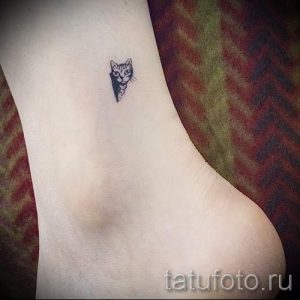 Фото тату с изображением миниатюрной мордочки кота, расположенной на лодыжке. Нежный и изящный рисунок татуировки.