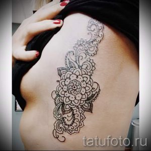 Фото тату: изящная мандала, выполненная в технике blackwork, на боку. Идея для женской татуировки с геометрическим узором.